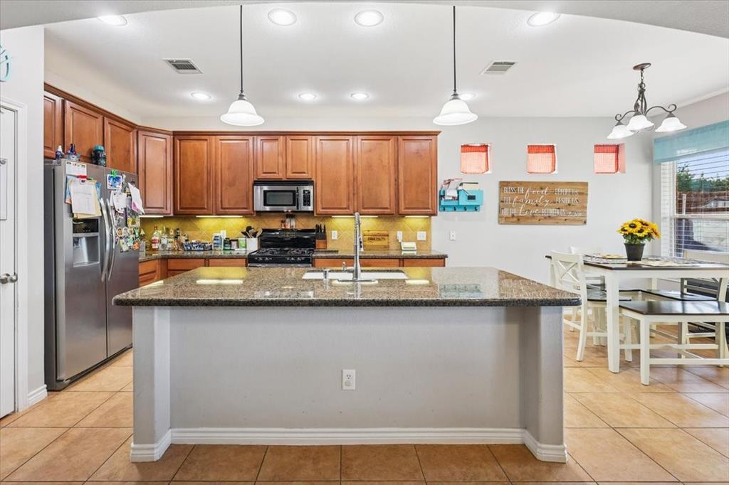 868 Valley Ridge Road Burleson, TX 76028 - Photo 8 of 39 a kitchen with stainless steel appliances granite countertop a sink a stove a refrigerator cabinets and chairs