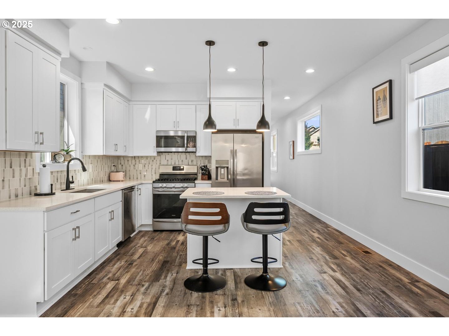 5424 Southeast Knapp Street Portland, OR 97206 - Photo 5 of 35 a kitchen with a refrigerator a stove and white cabinets with wooden floor