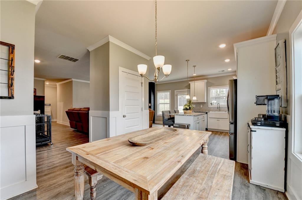 1179 Simmons Road Social Circle, GA 30025 - Photo 11 of 71 a large kitchen with kitchen island a stove a sink a refrigerator and a dining table with wooden floor