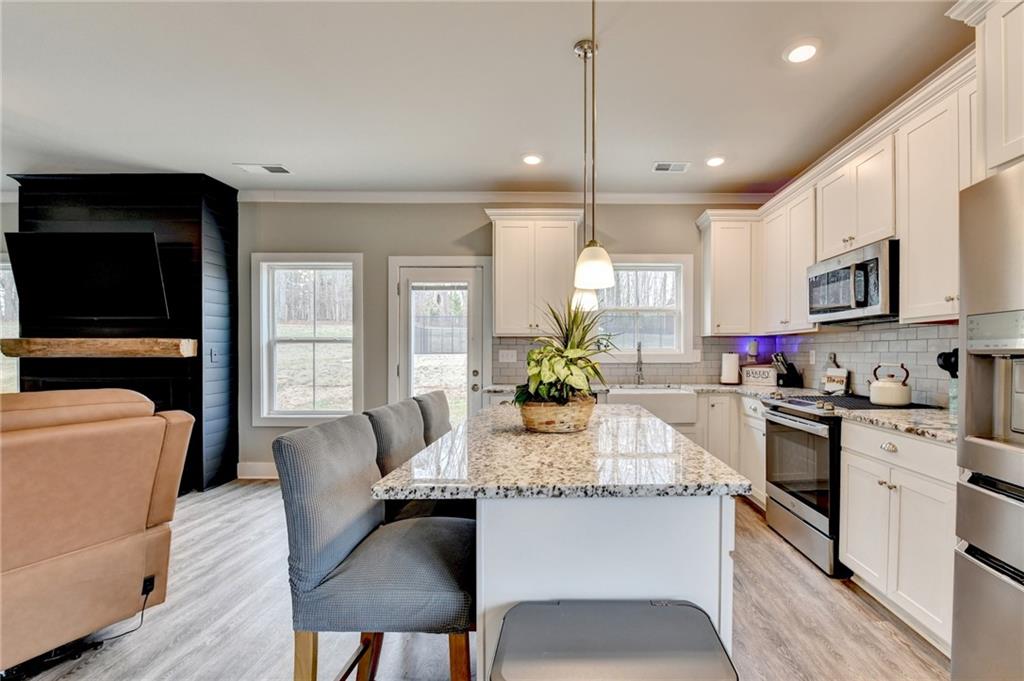 1179 Simmons Road Social Circle, GA 30025 - Photo 13 of 71 a kitchen with stainless steel appliances granite countertop a stove top oven a sink dishwasher a dining table and chairs with wooden floor