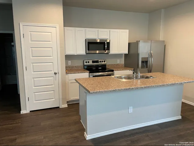 a kitchen with kitchen island a sink stainless steel appliances and wooden floor