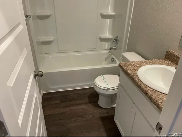 a bathroom with a granite countertop bathtub shower sink vanity and toilet