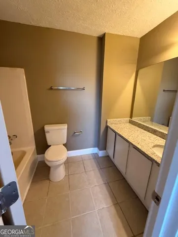 a bathroom with a granite countertop sink a toilet and a mirror