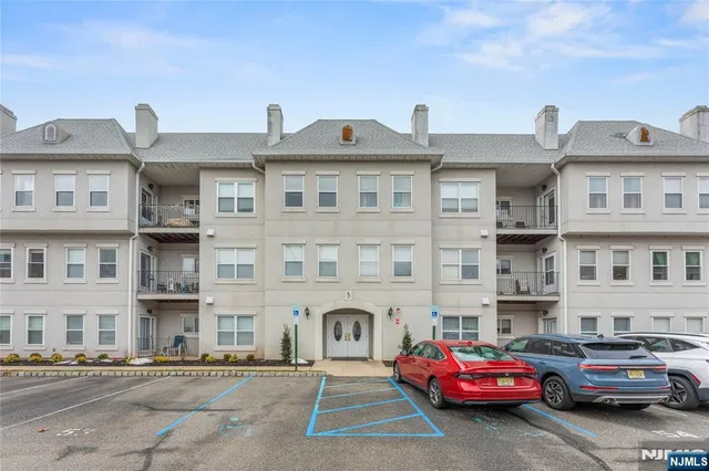 a front view of a residential apartment building with cars parked