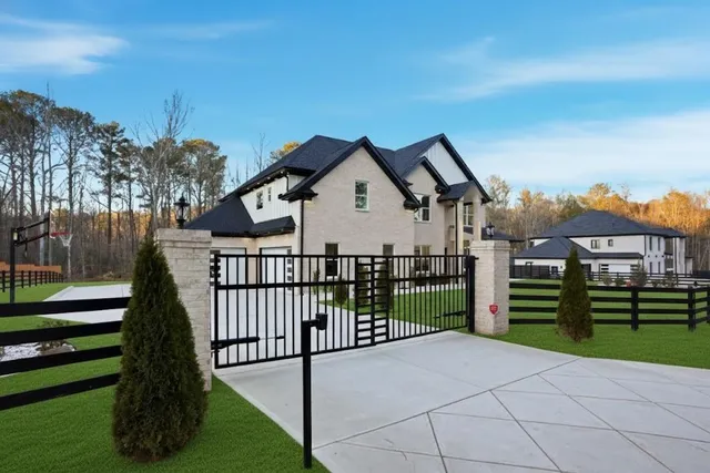 a view of a white house with a small yard and wooden fence