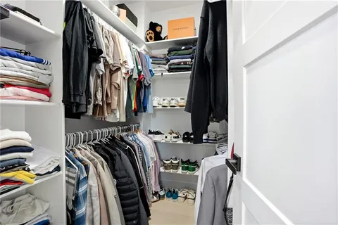 a view of walk in closet with clothes and shoes