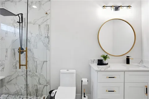 a bathroom with a granite countertop sink mirror vanity and toilet