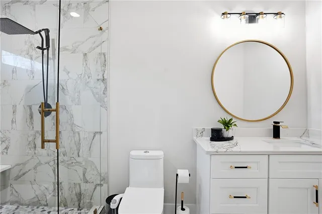 a bathroom with a granite countertop sink mirror vanity and toilet