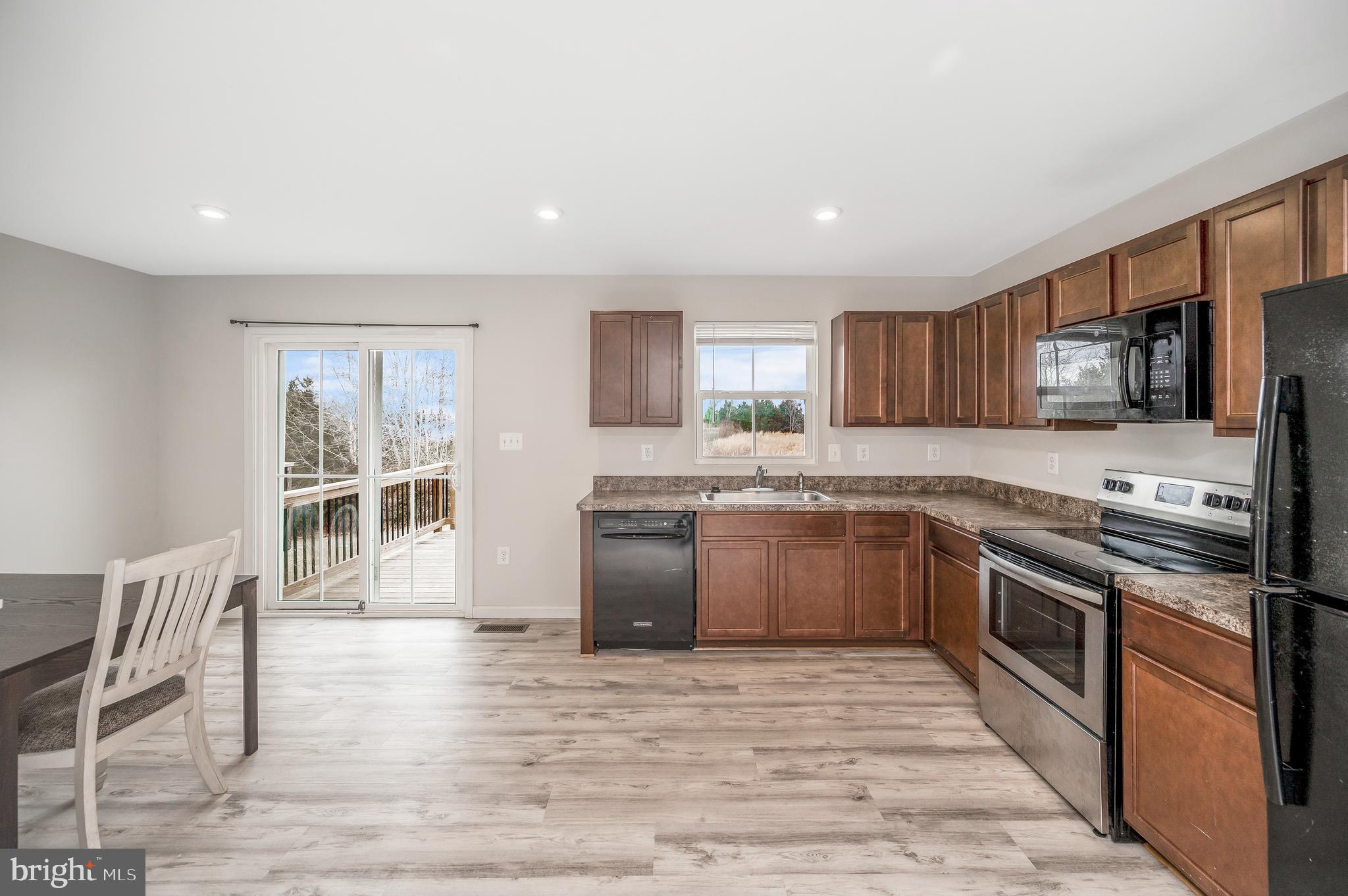 35252 Sara Court Locust Grove, VA 22508 - Photo 11 of 40 a kitchen with stainless steel appliances granite countertop a stove top oven a sink dishwasher a dining table and chairs with wooden floor