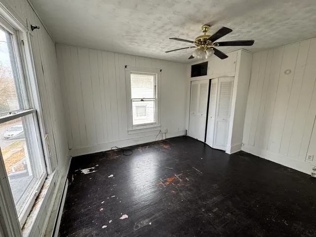 an empty room with wooden floor cabinet and windows