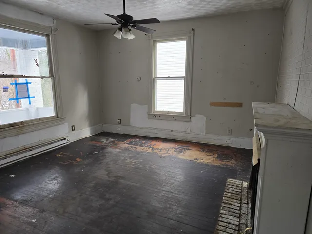 an empty room with wooden floor cabinet and windows