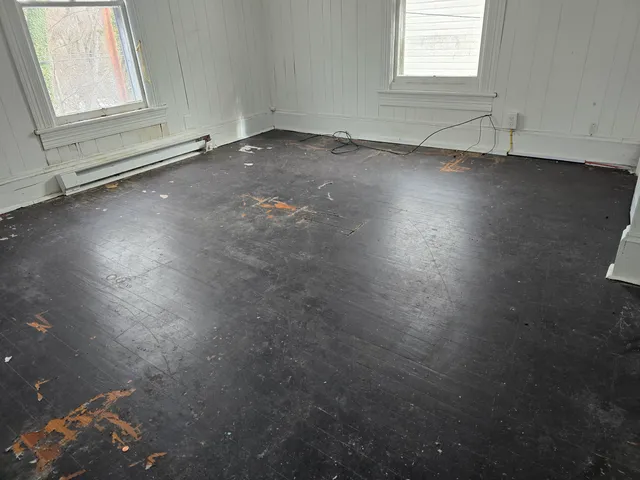 an empty room with wooden floor and windows