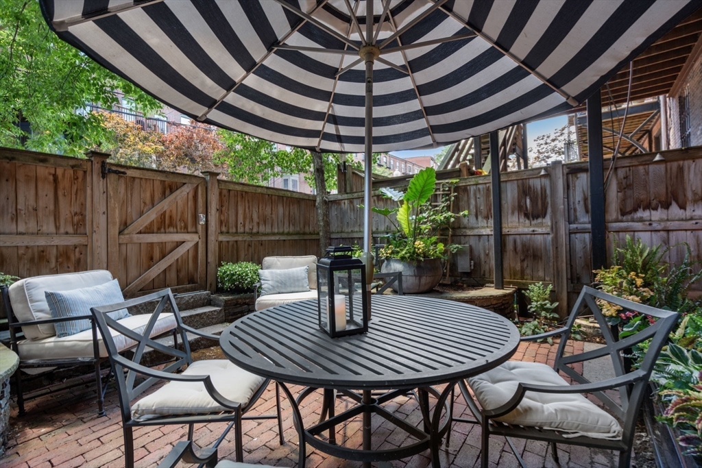 32 Rutland Square, Unit 1 Boston, MA 02118 - Photo 20 of 24 a view of patio with table and chairs potted plants and floor to ceiling window with wooden fence