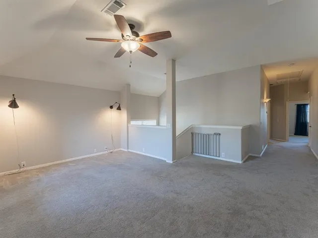 a view of an empty room with a chandelier fan