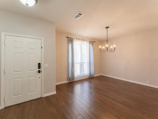 an empty room with wooden floor and ceiling fan