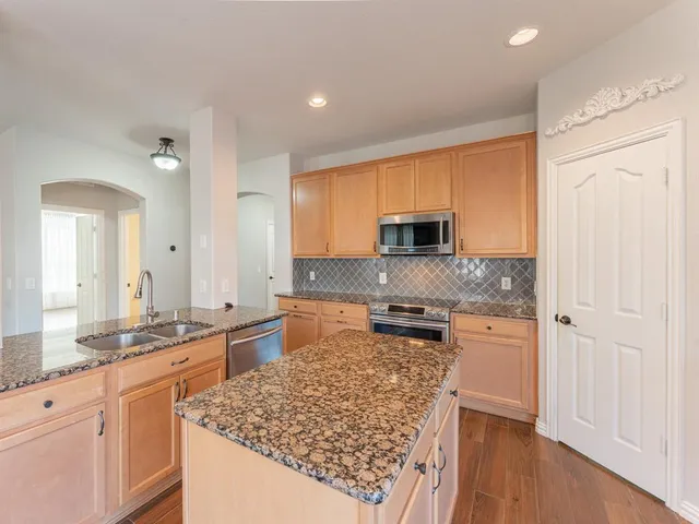 a large kitchen with kitchen island granite countertop wooden cabinets a granite counter and a sink