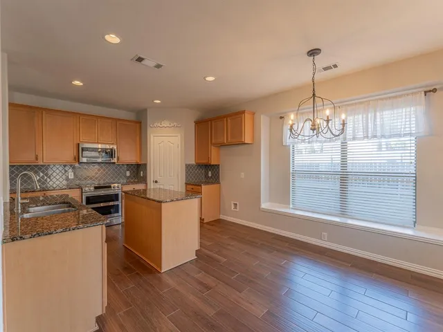 a kitchen with kitchen island a sink a stove a refrigerator cabinets and wooden floor