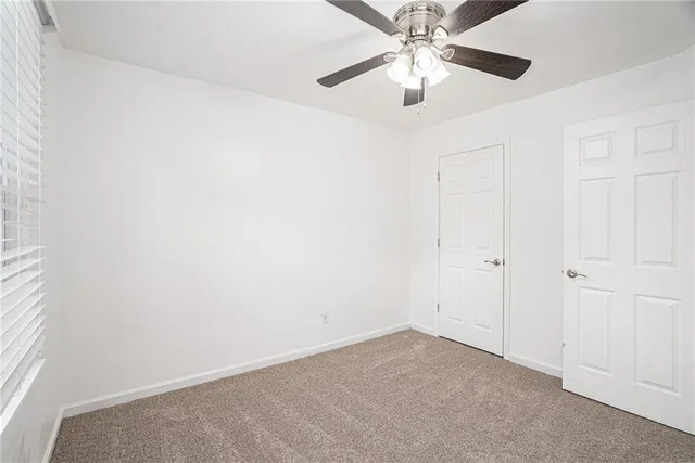 an empty room with closet and a chandelier fan