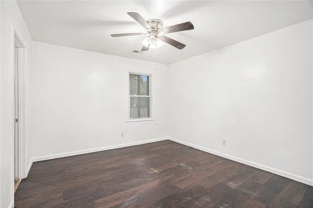 an empty room with wooden floor and ceiling fan