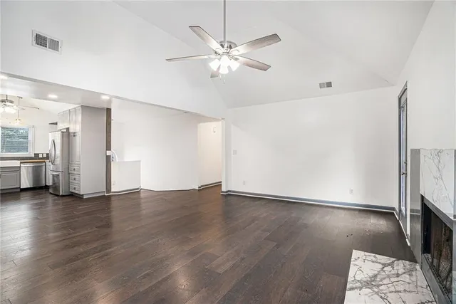a view of an empty room with wooden floor and a ceiling fan
