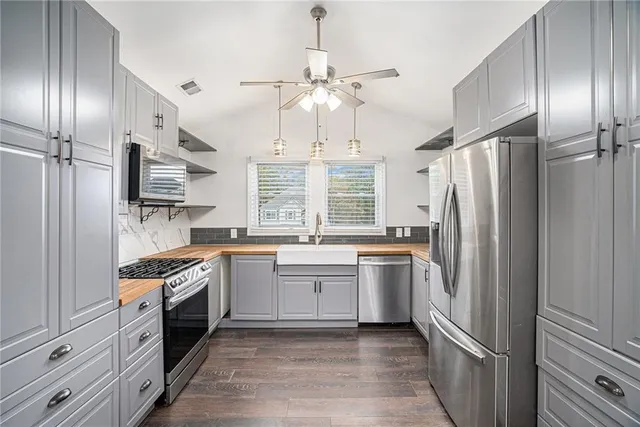 a kitchen with stainless steel appliances granite countertop a refrigerator a stove and a sink