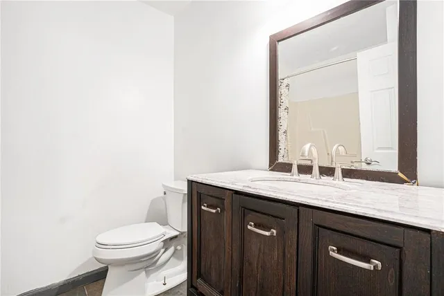a bathroom with a granite countertop toilet sink and mirror