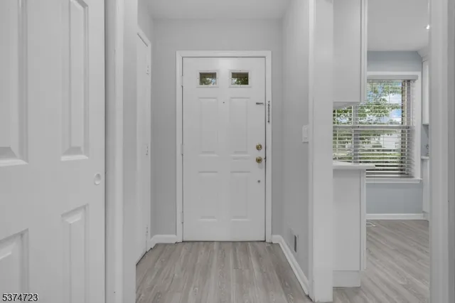 a view of a hallway with wooden floor and a bathroom