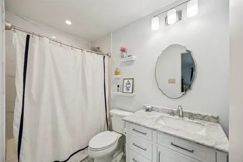 a bathroom with a granite countertop sink toilet and a mirror