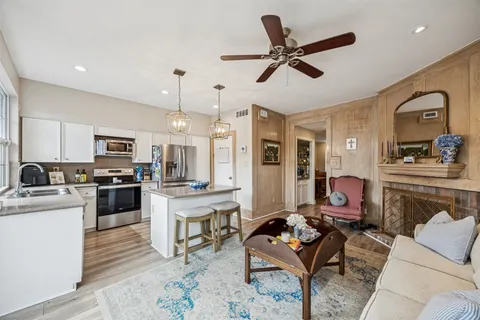 a living room with furniture kitchen area and a stove