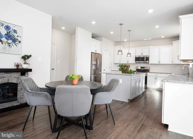 a kitchen with refrigerator a stove a dining table and chairs with wooden floor