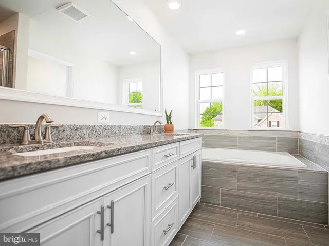 a bathroom with a granite countertop double vanity sink and a window