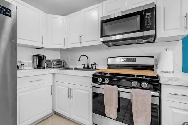 a kitchen with white cabinets stainless steel appliances and wooden cabinets
