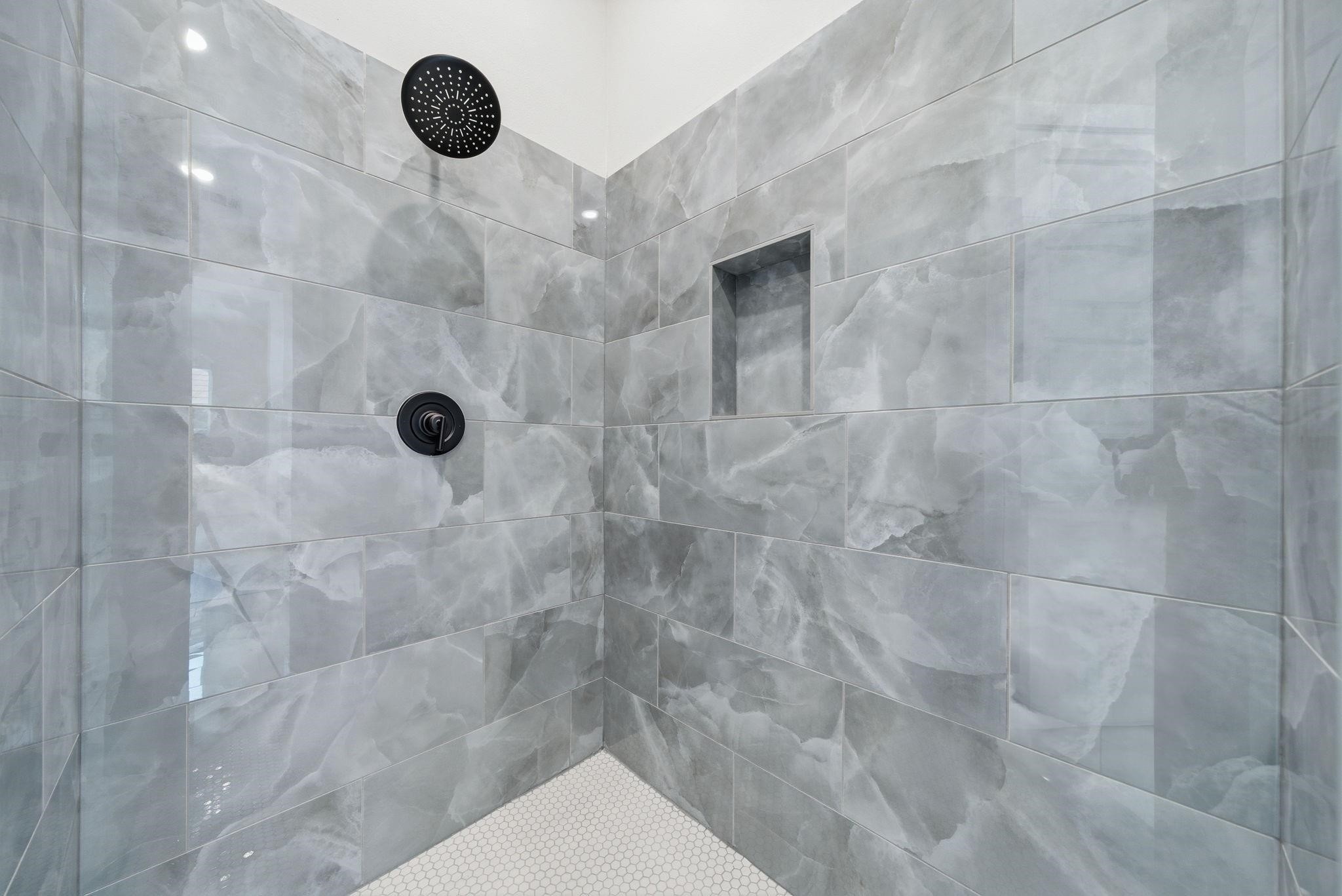 4013 Griggs Road, Unit F Houston, TX 77021 - Photo 7 of 35 Luxurious shower featuring elegant gray marble tiles, a sleek rain shower head, and a convenient recessed shelf for toiletries.