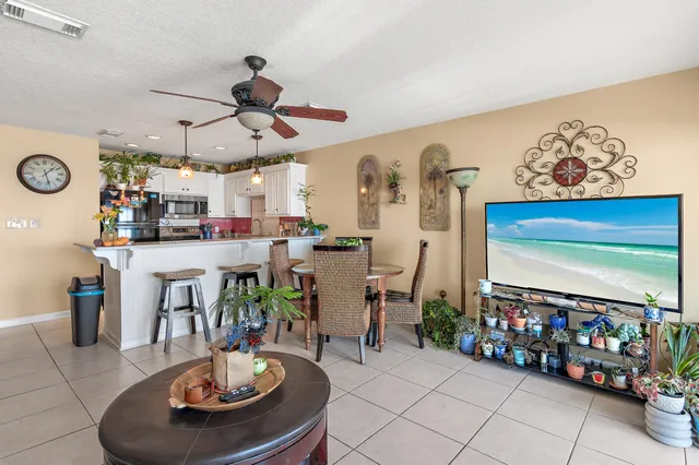 a room with lots of white furniture a chandelier and a table