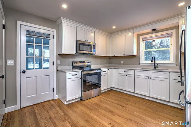 a kitchen with stainless steel appliances white cabinets a sink a stove a refrigerator and microwave