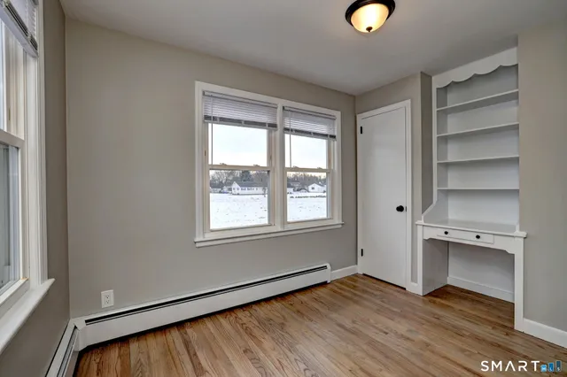 a view of an empty room with a window and wooden floor