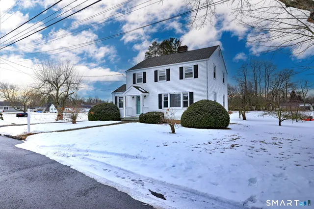 a view of a white house with a yard covered in snow