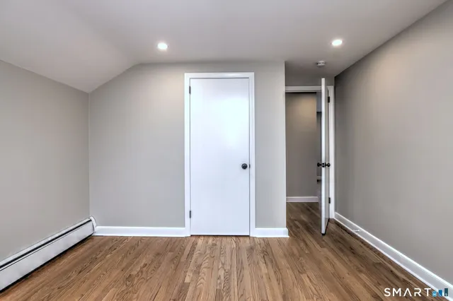 an empty room with wooden floor and entrance