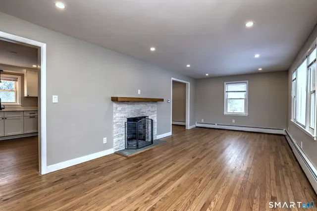 an empty room with wooden floor fireplace and windows