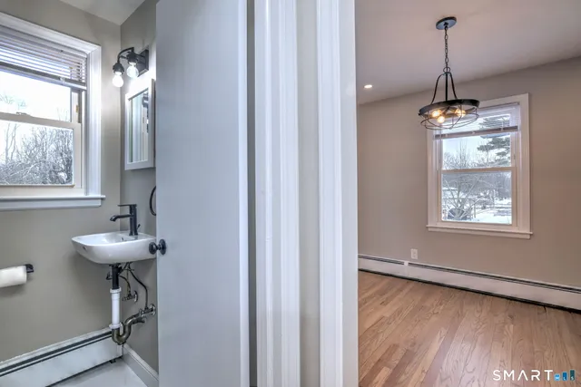 a dining room with wooden floor a chandelier a wooden table and chairs