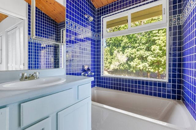 a bathroom with a granite countertop sink and a bathtub
