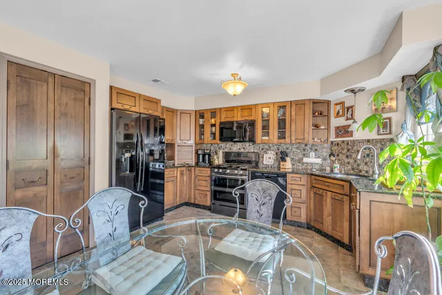 a kitchen with stainless steel appliances granite countertop a refrigerator a stove top oven and a dining table with wooden floor