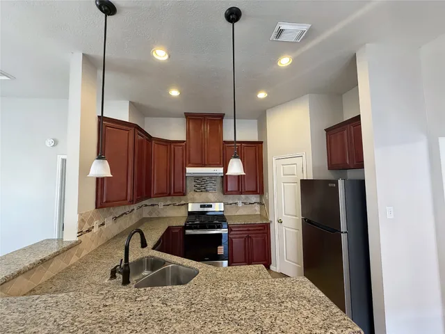 a kitchen with stainless steel appliances granite countertop a sink refrigerator and cabinets