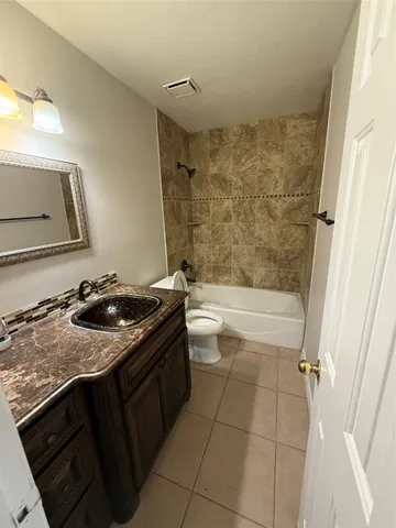 a bathroom with a granite countertop sink a toilet and bathtub