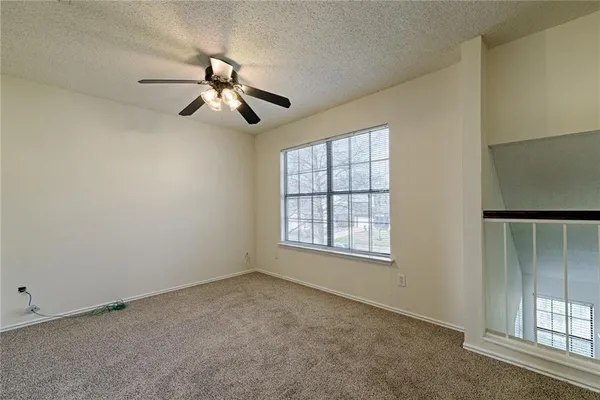 an empty room with windows and fan