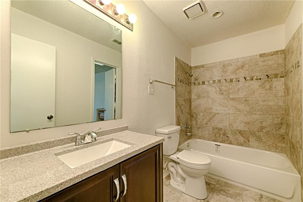 4652 Misty Ridge Drive Fort Worth, TX 76137 - Photo 16 of 24 a bathroom with a granite countertop sink toilet mirror and bathtub
