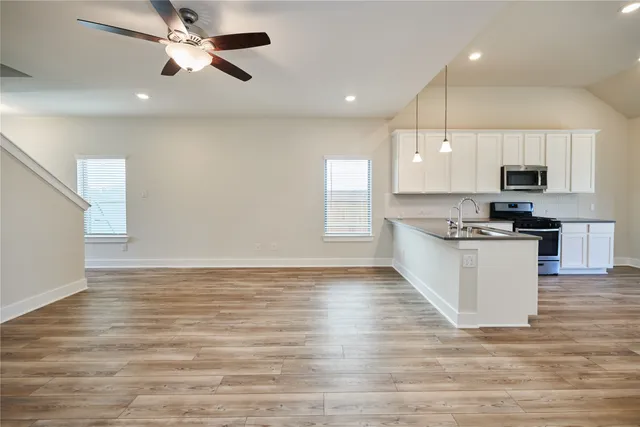 a view of kitchen with microwave a stove and white cabinets