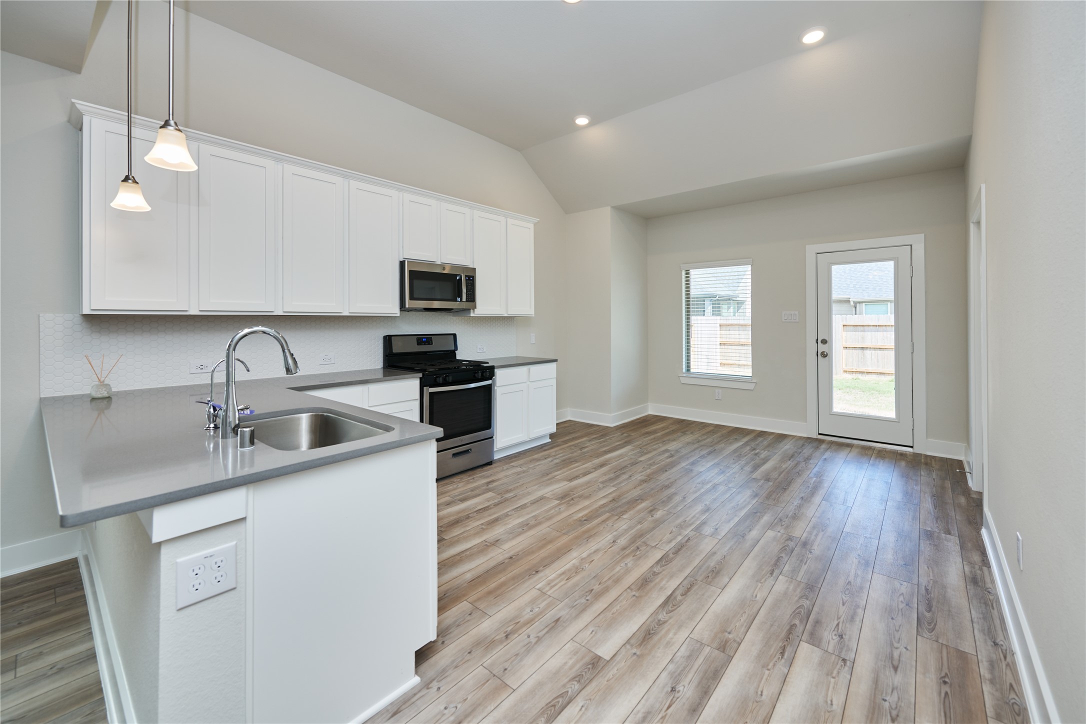 10647 Whitejacket Conroe, TX 77385 - Photo 13 of 38 a kitchen with a sink dishwasher a microwave oven and a stove with wooden floor