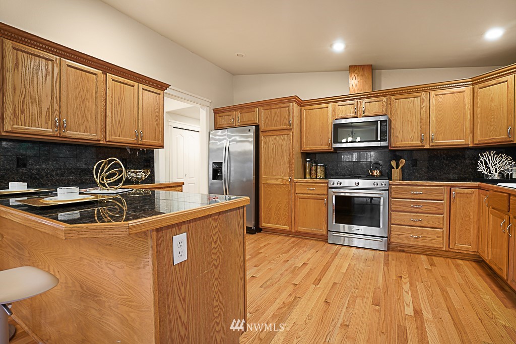 2806 183rd Avenue Northeast Redmond, WA 98052 - Photo 16 of 40 a kitchen with stainless steel appliances a refrigerator a stove a sink cabinets and wooden floor