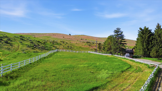 2075 Canyon Road Smithfield, UT 84335 - Photo 17 of 18 Expansive fenced pasture with lush green grass and rolling hills in the background